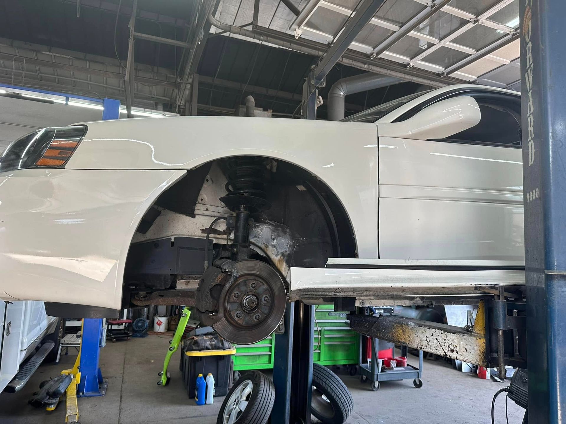 A white car is sitting on a lift in a garage.