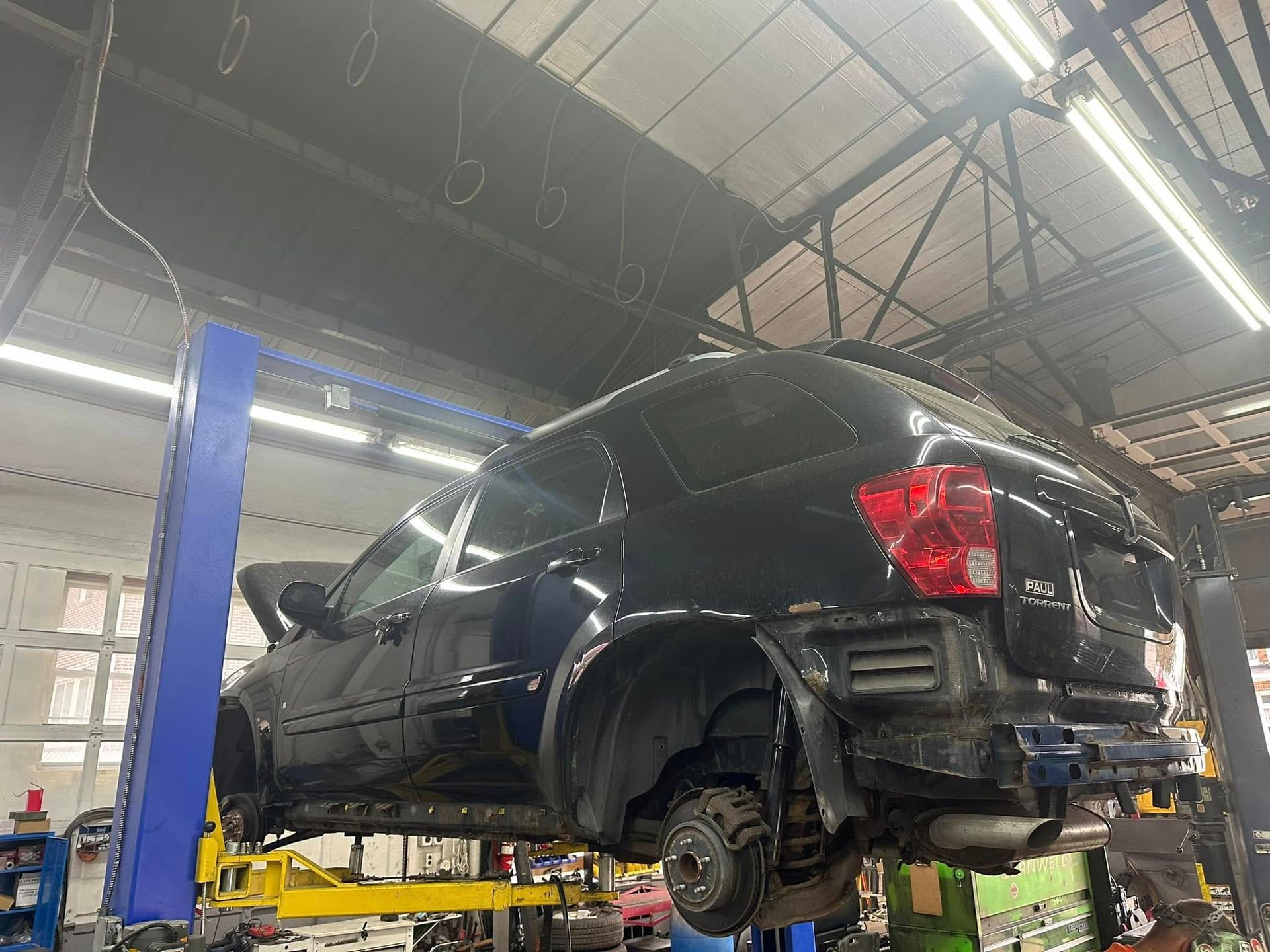 A black car is sitting on a lift in a garage.