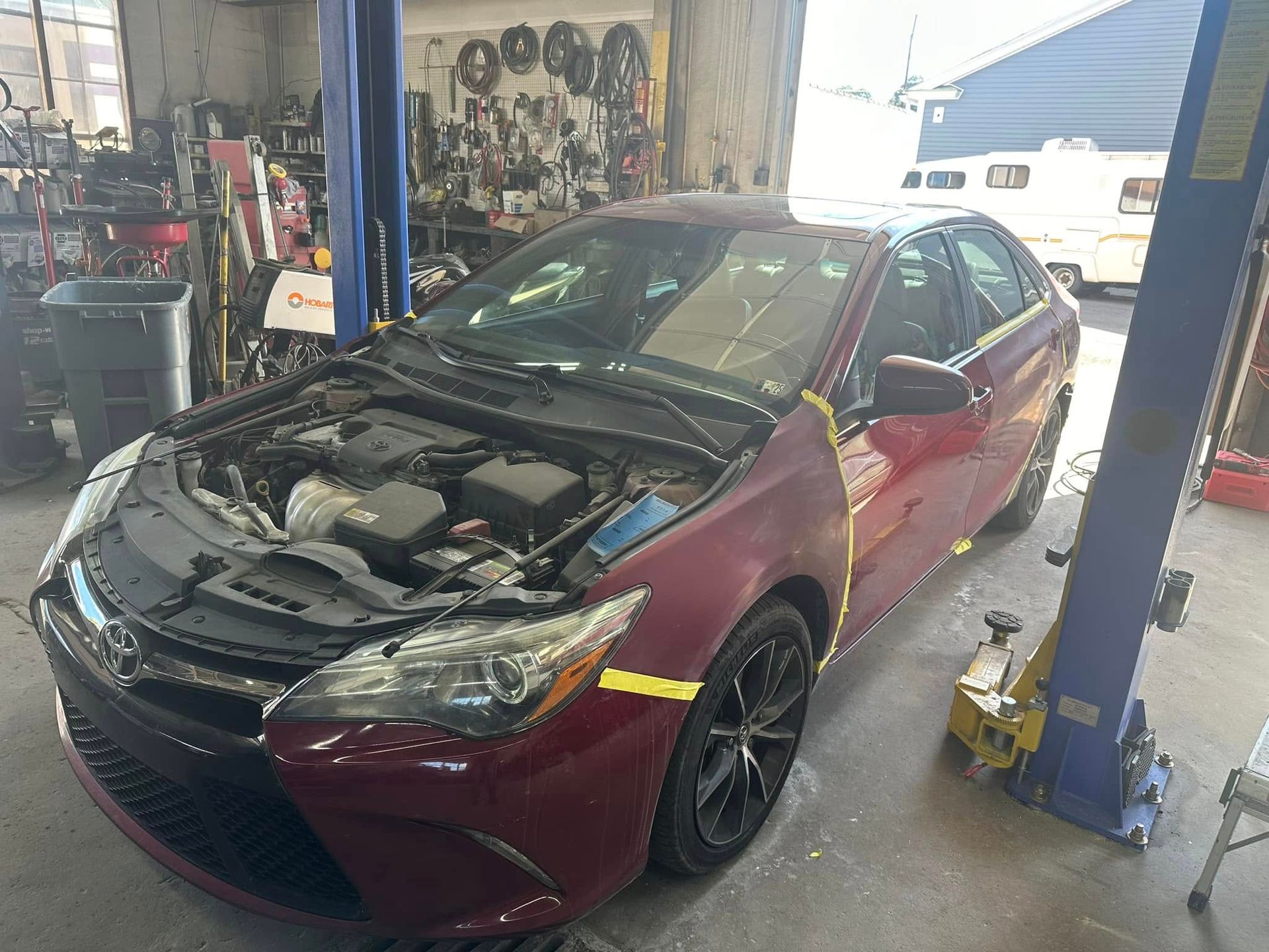 A red car is sitting on a lift in a garage.