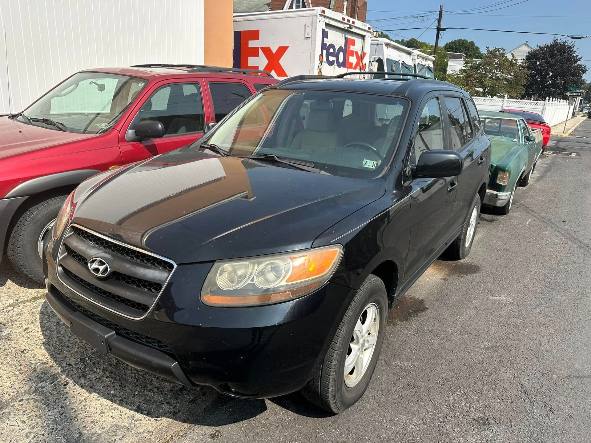A black suv is parked in front of a fedex truck.
