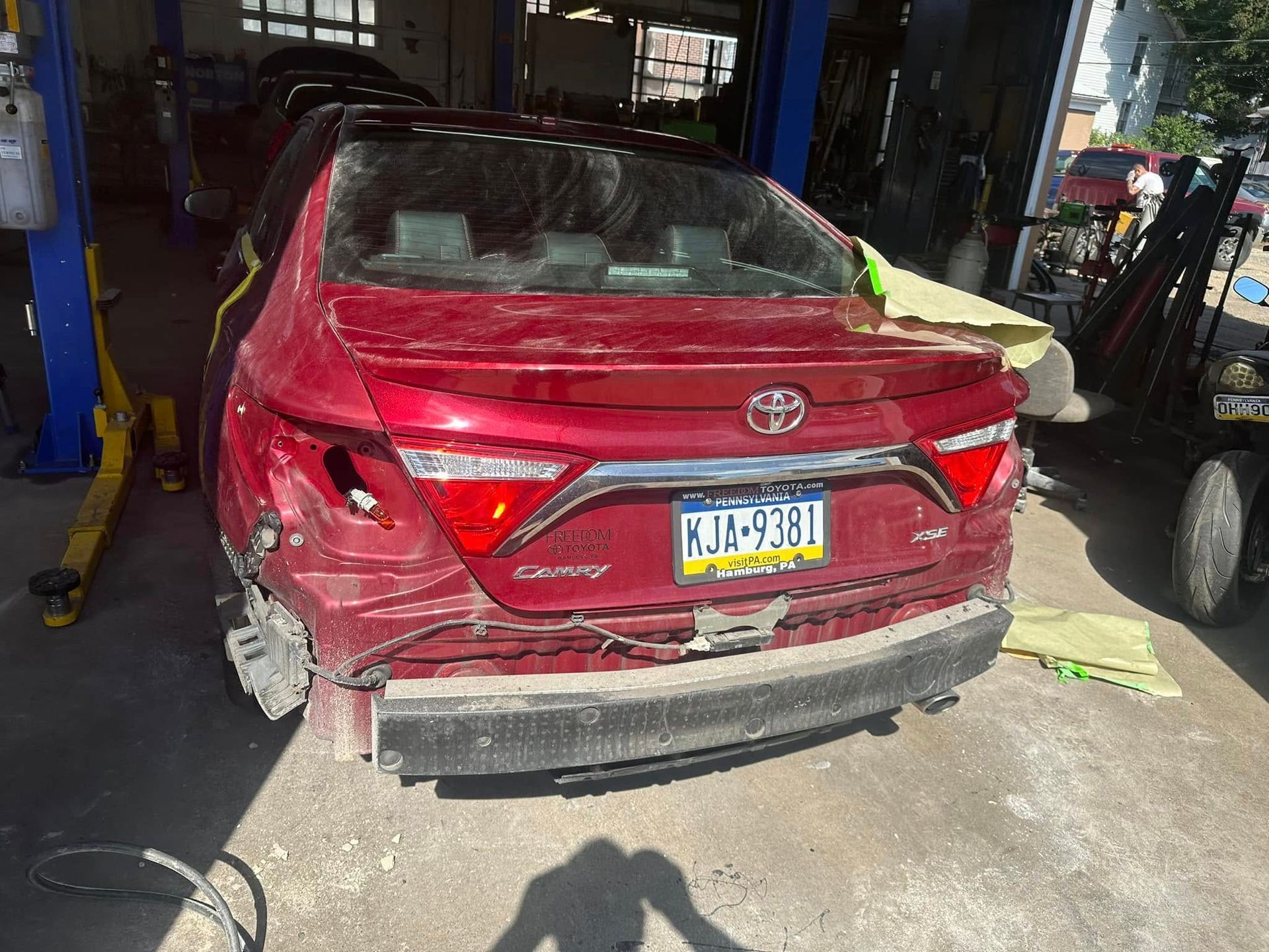 A red toyota camry is sitting on a lift in a garage.