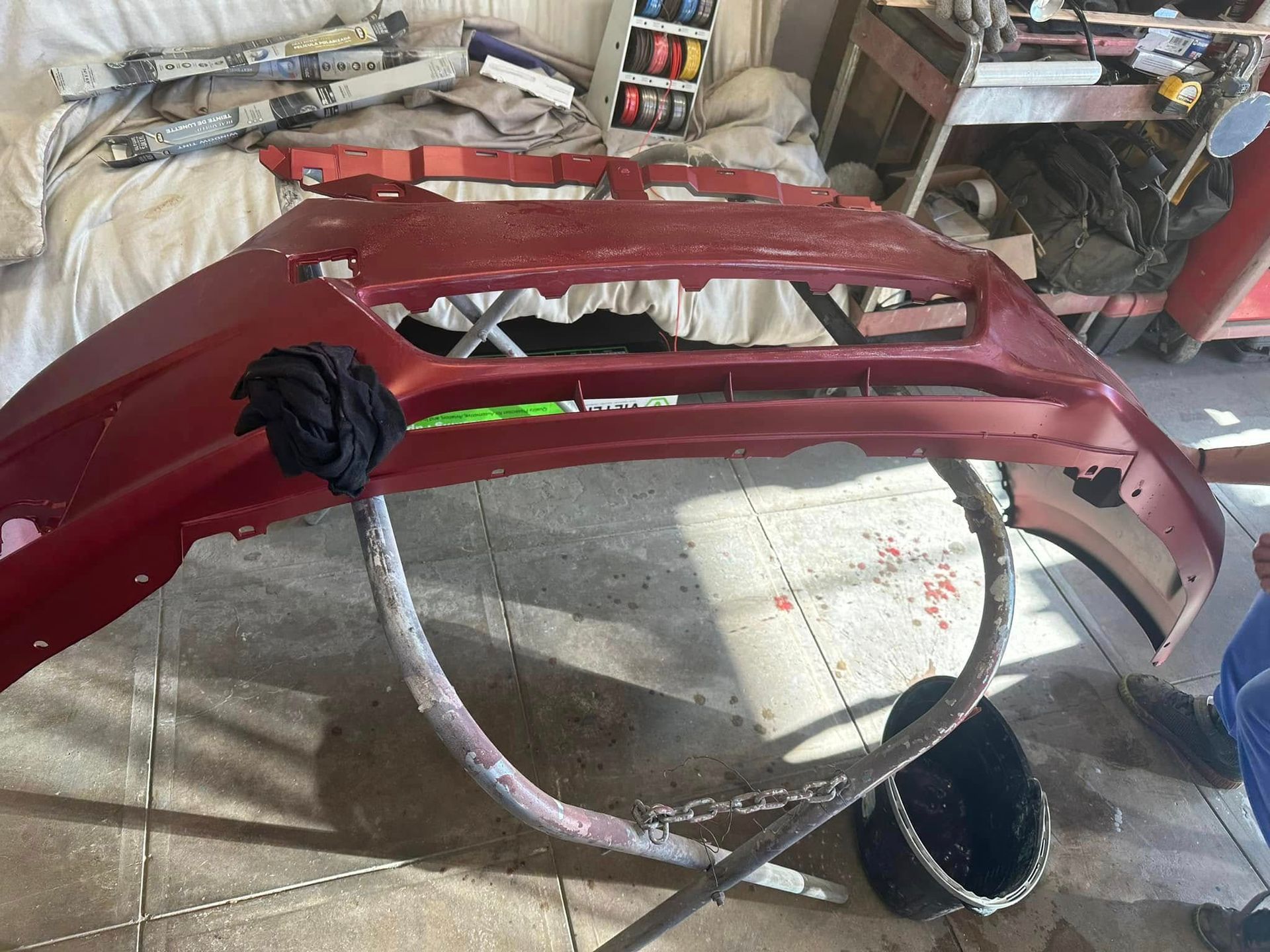 A red bumper is sitting on a tiled floor in a garage.