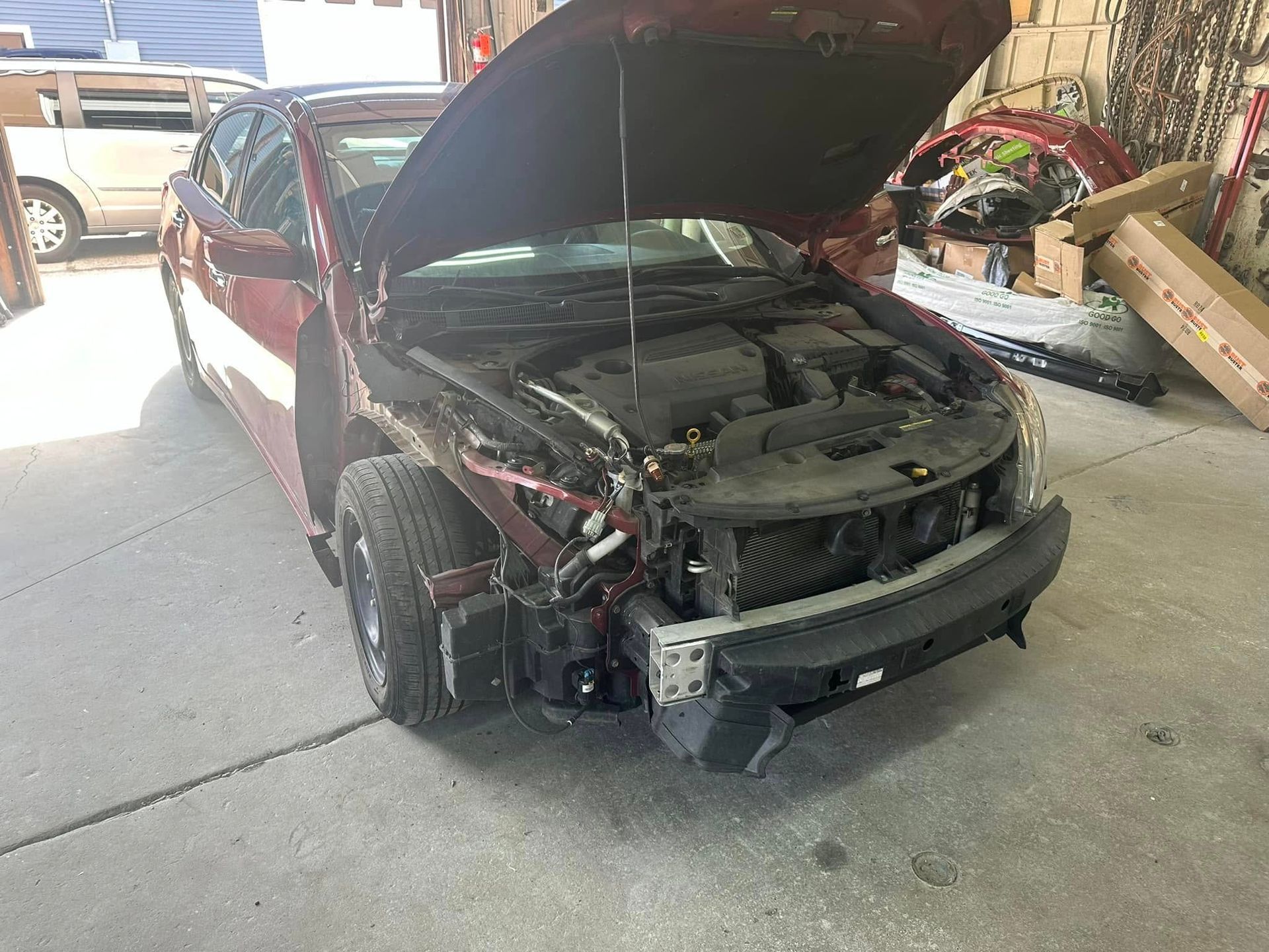 A red car with the hood up is sitting in a garage.