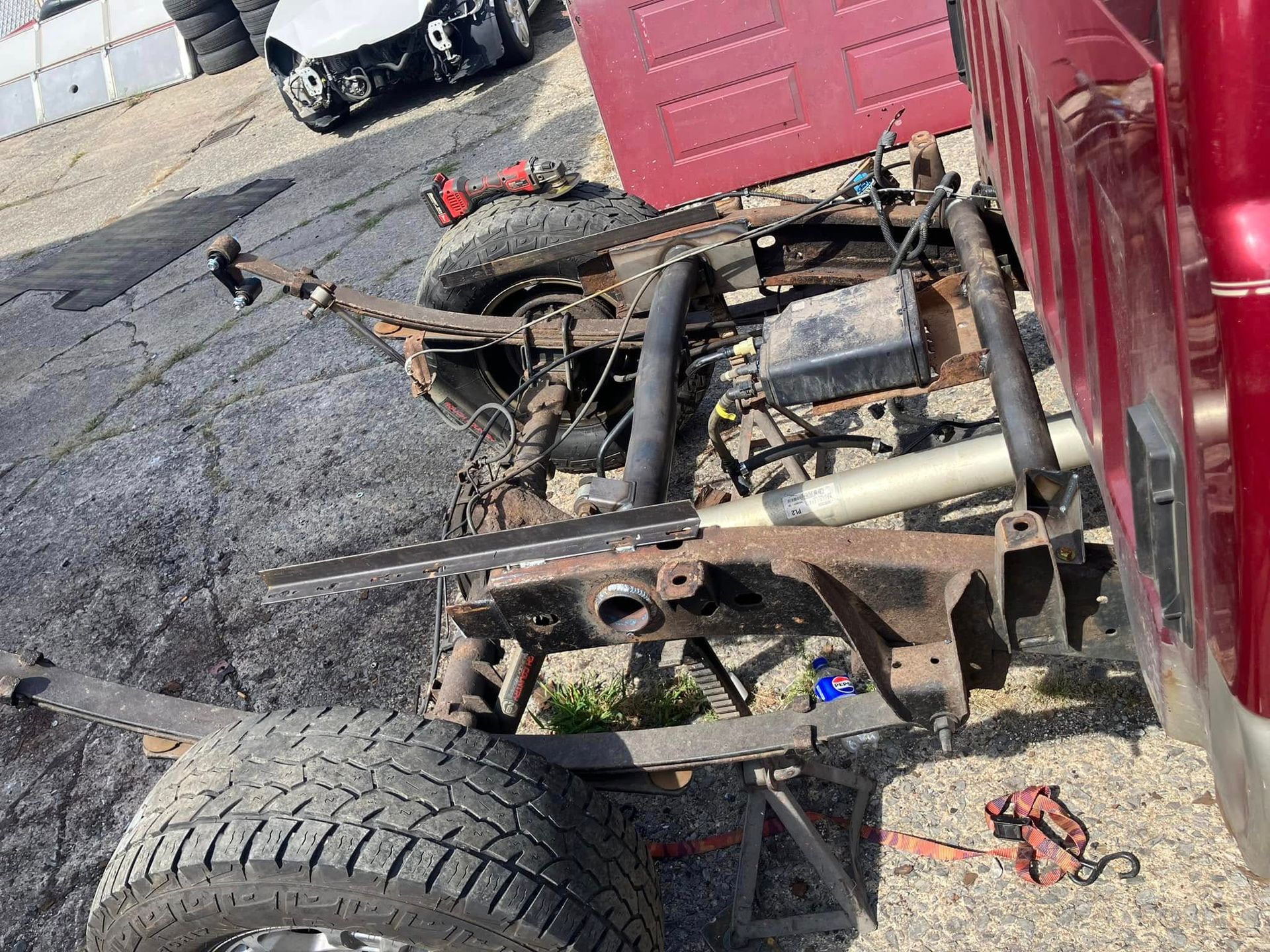 A red truck is being dismantled on the side of the road.