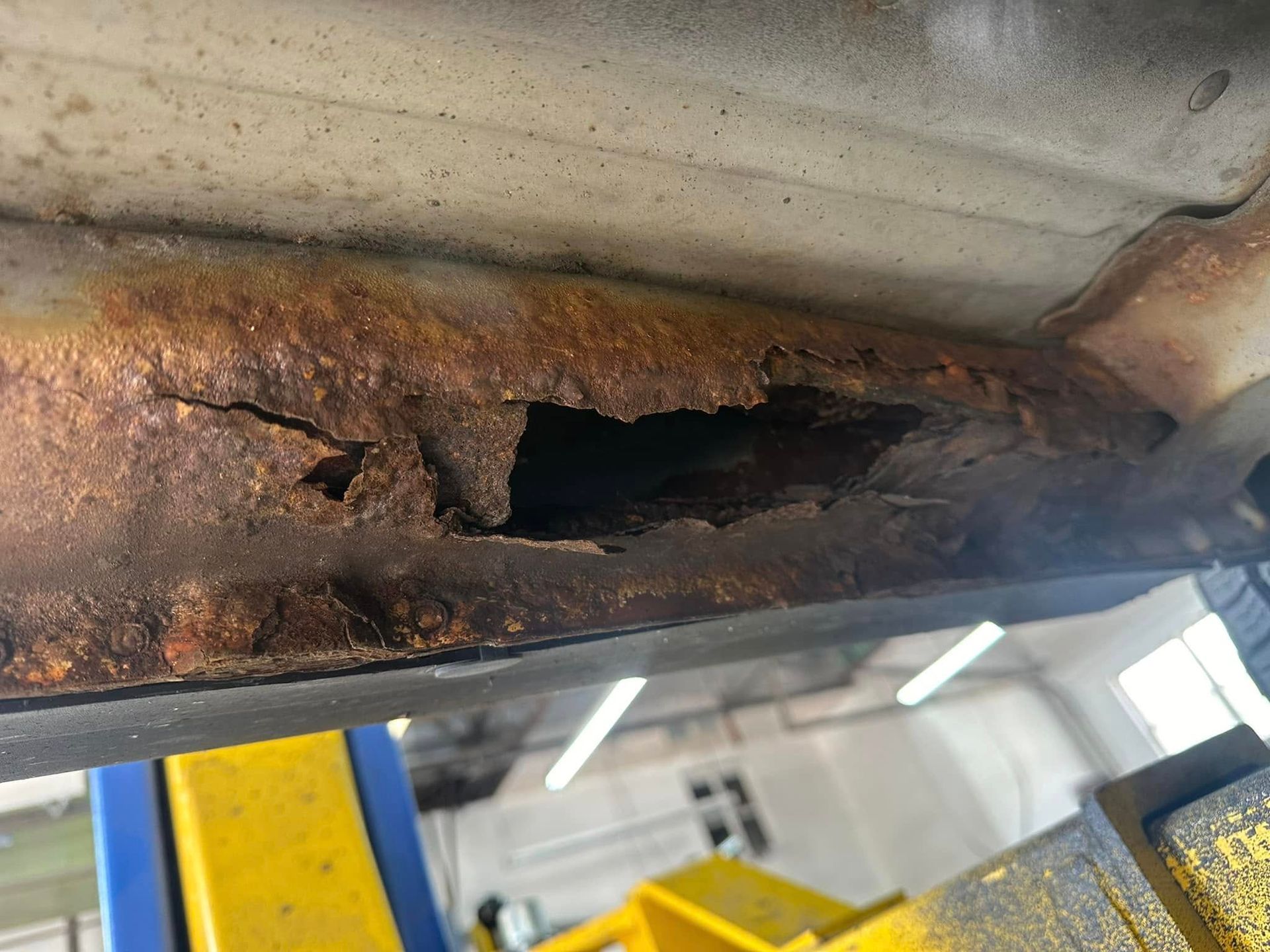 A piece of rusty metal is sitting on top of a yellow and blue lift.