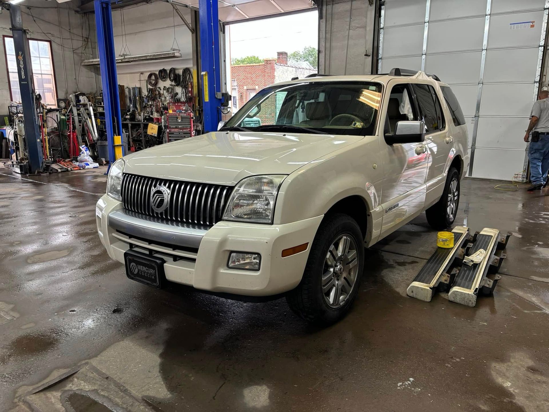 A white mercury mountaineer is parked in a garage.