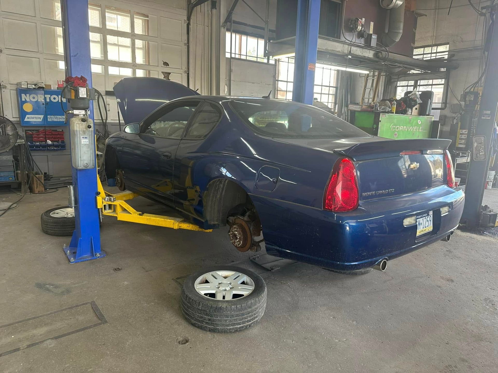 A blue car is sitting on a lift in a garage.