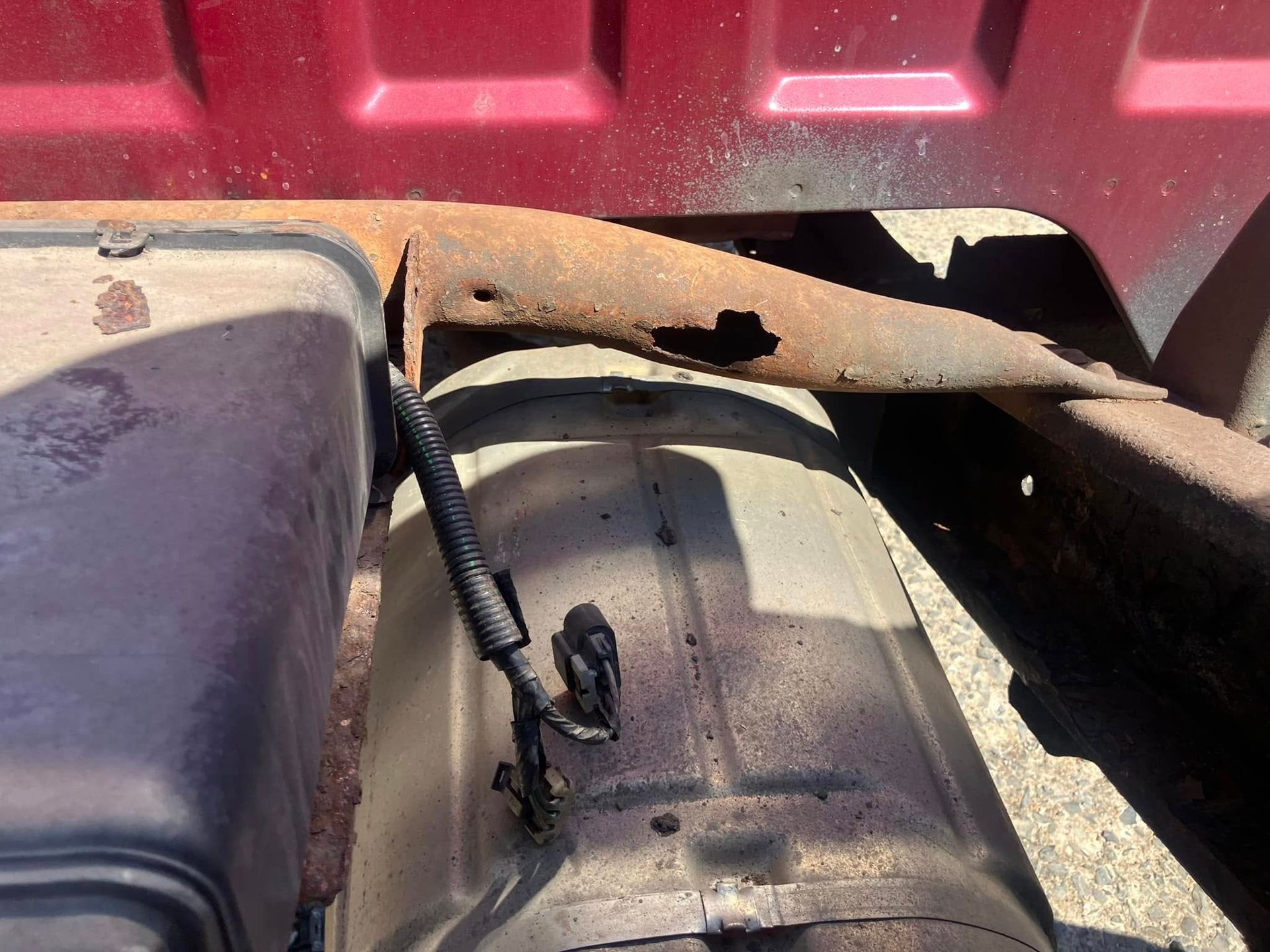 A close up of a rusty exhaust pipe on a red truck.