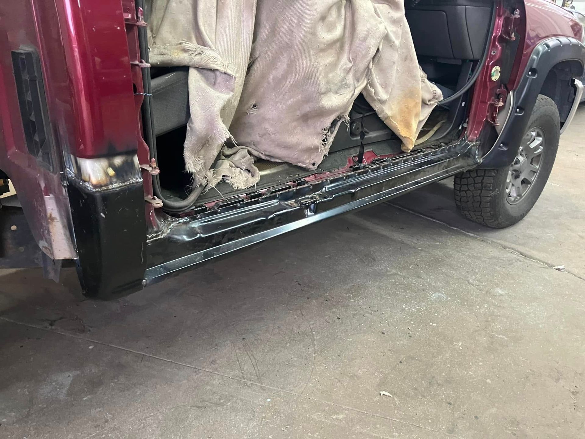 A red truck with the door open is parked on the side of the road.