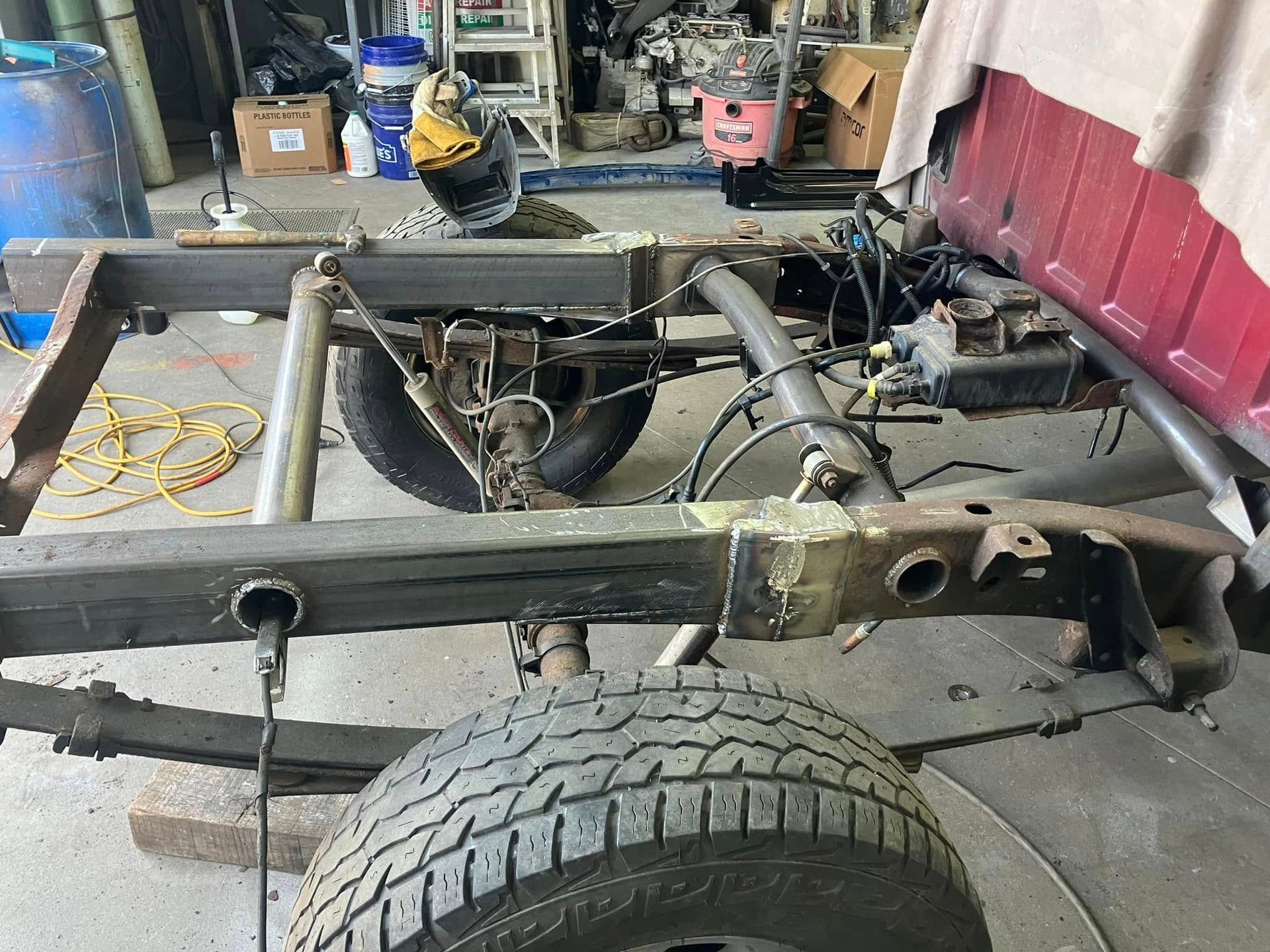 A truck is being built in a garage with a tire on the ground.