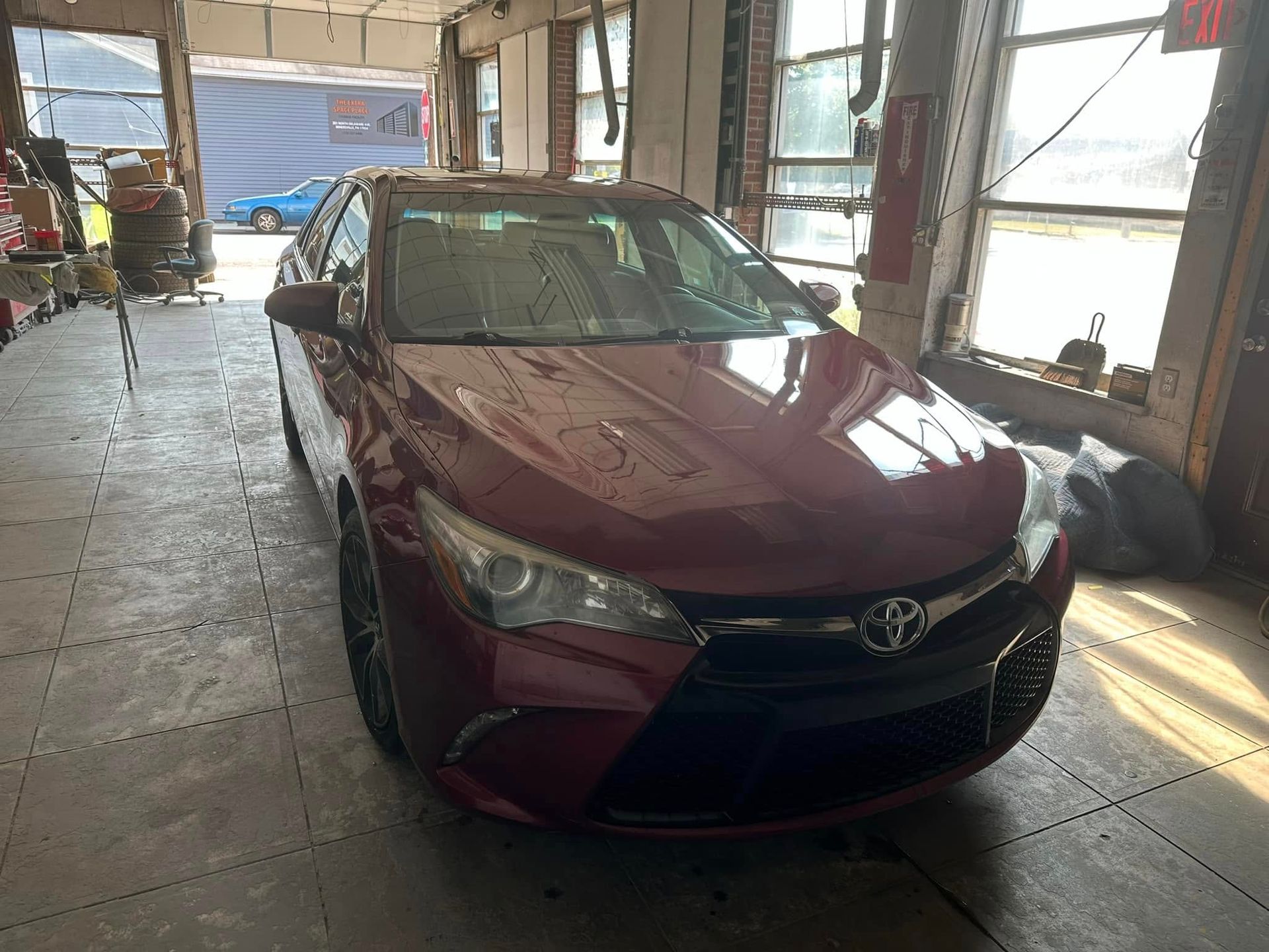 A red toyota camry is parked in a garage.