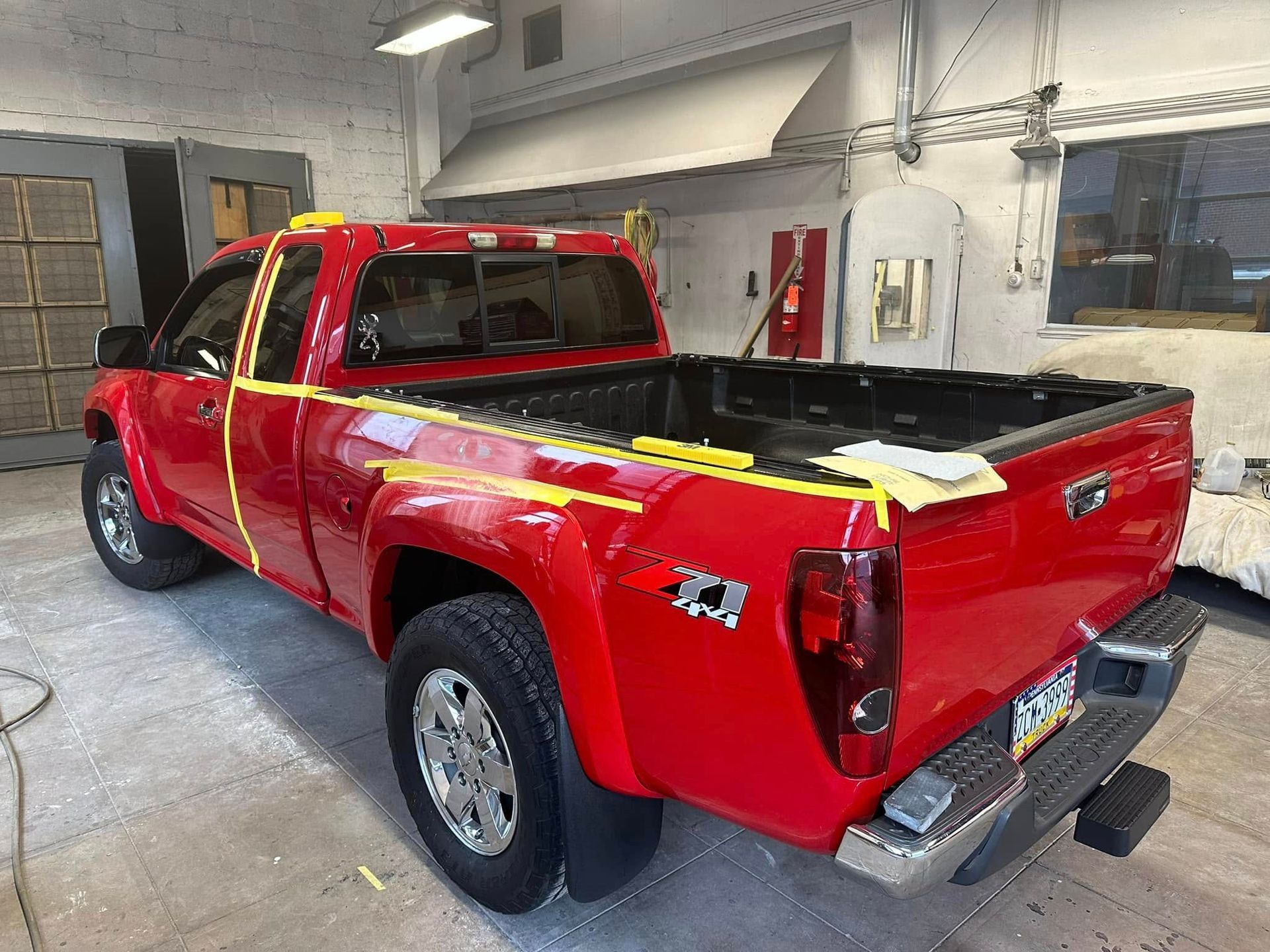 A red truck is being painted in a garage