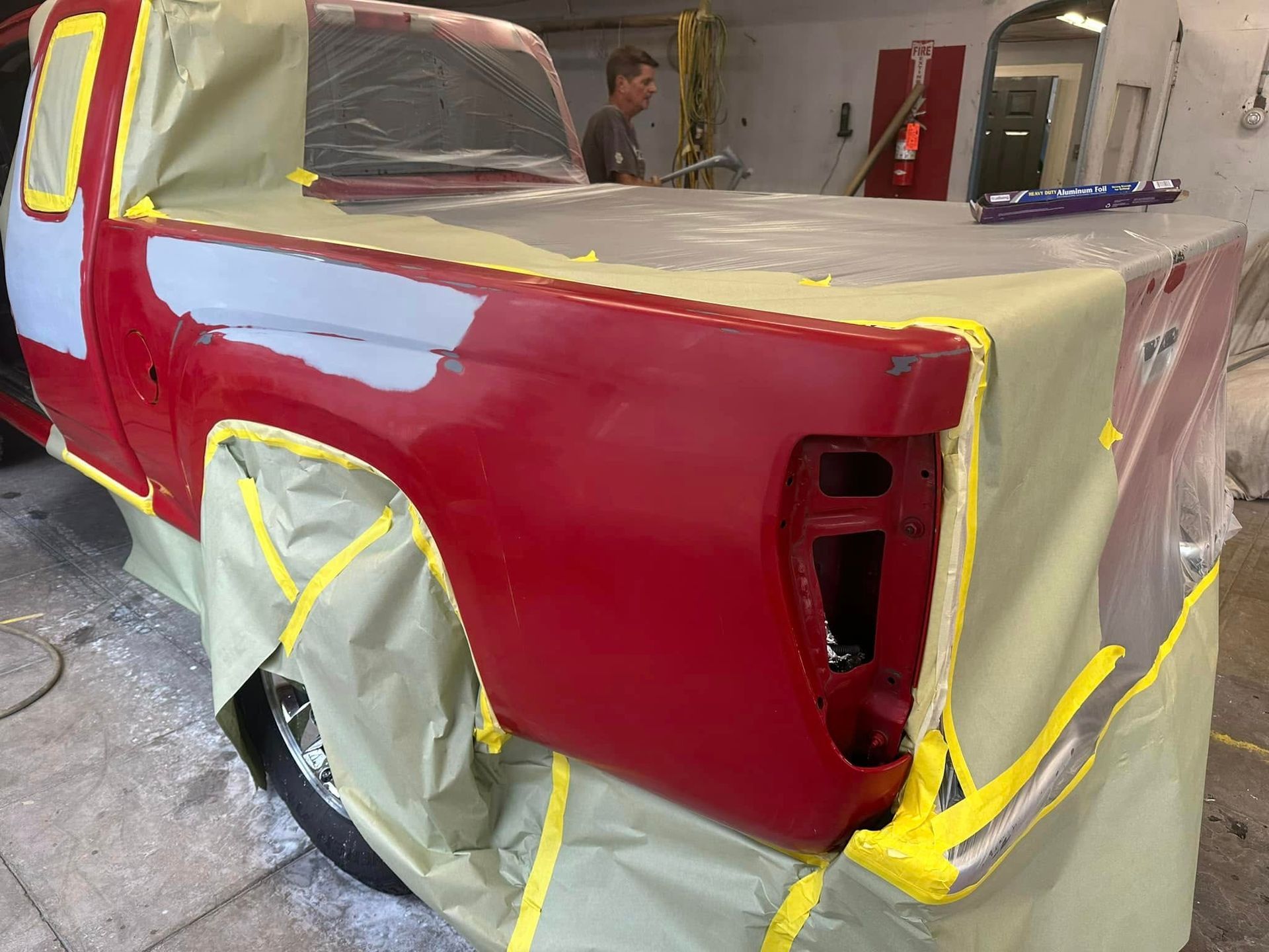 A red truck is being painted in a garage.