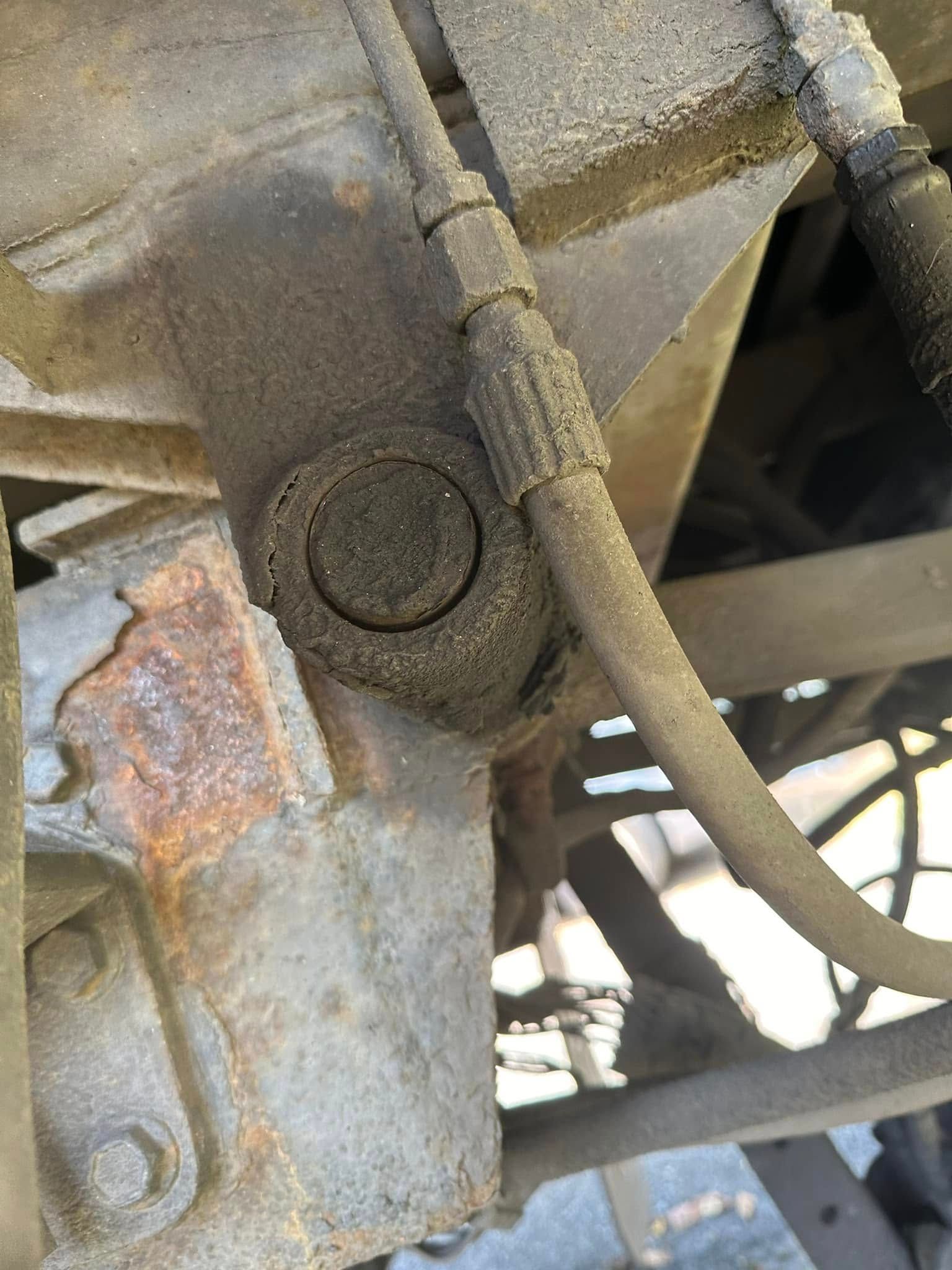 A close up of a rusty piece of metal with a hose attached to it.