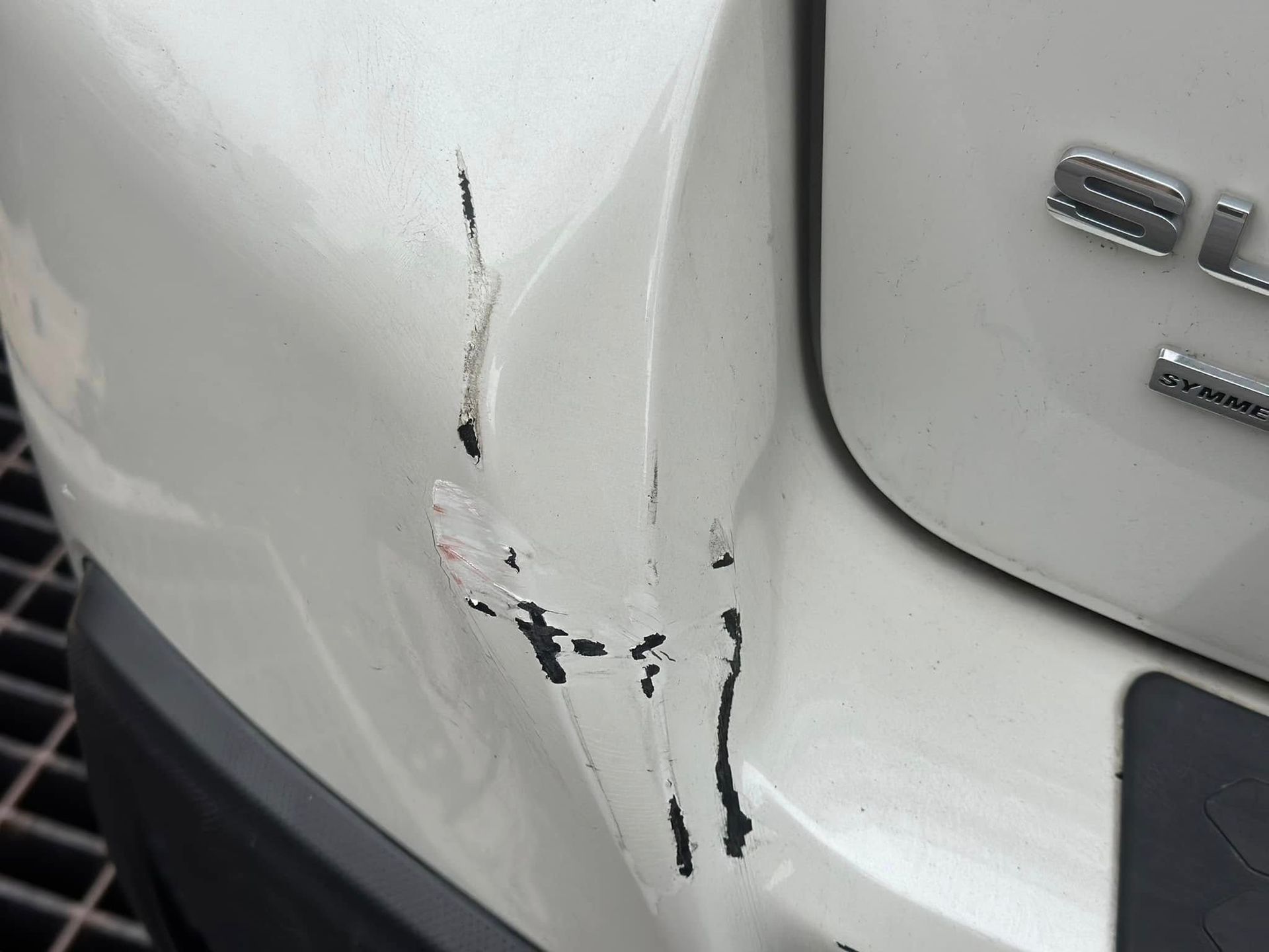 A close up of a white car with a damaged bumper