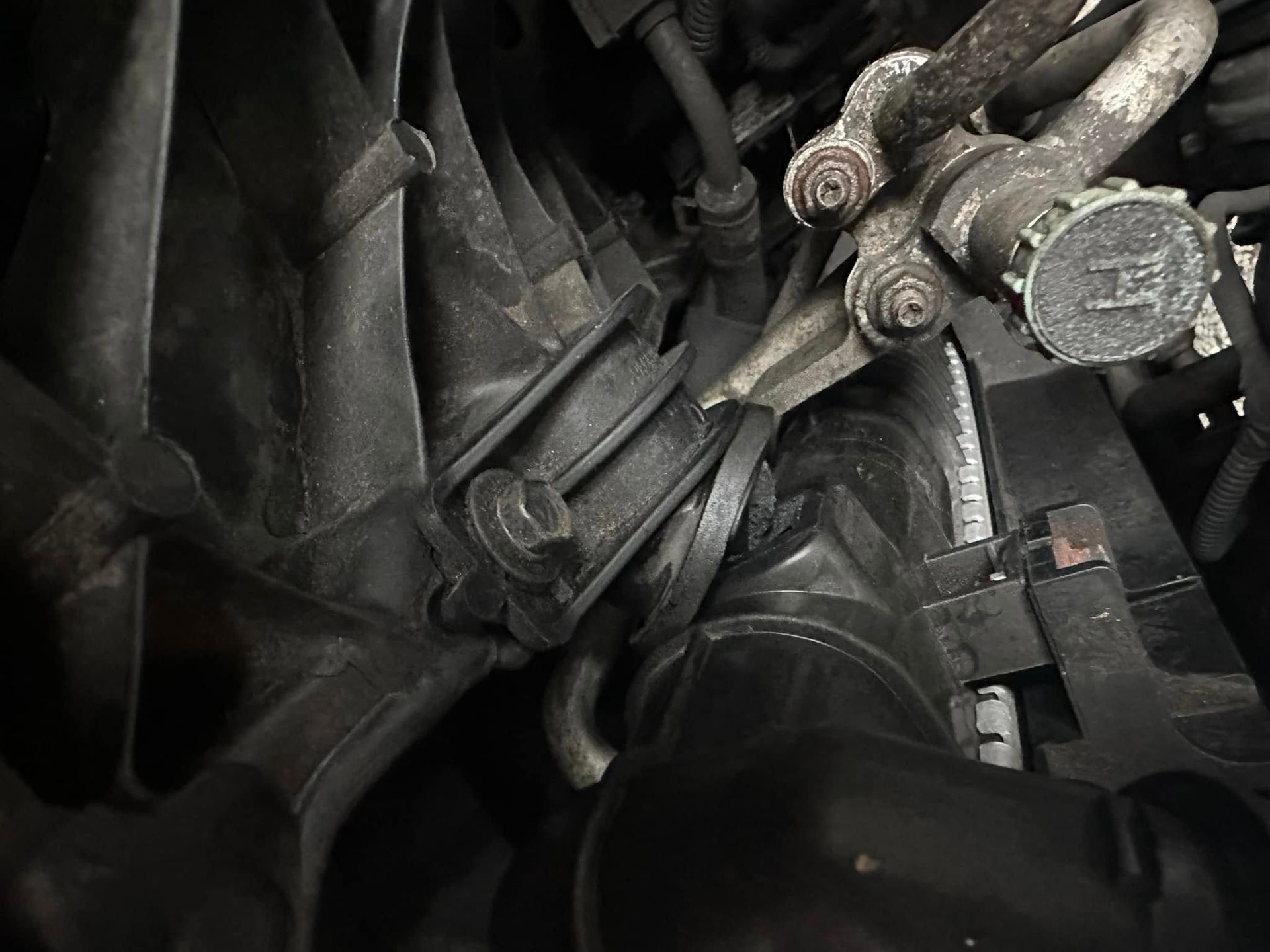 A close up of a car engine with a hose attached to it.