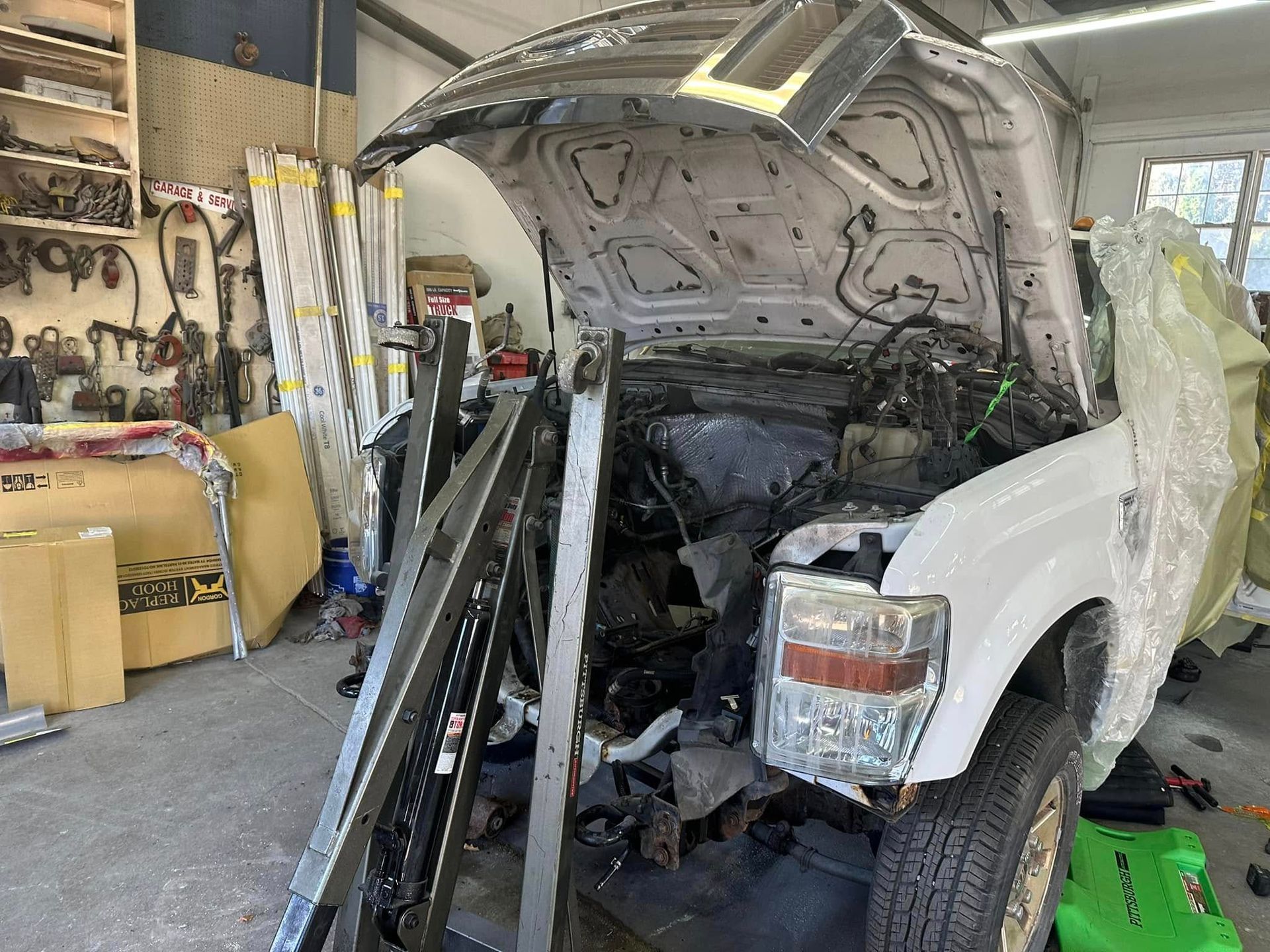 A car is being built in a garage with the hood up.