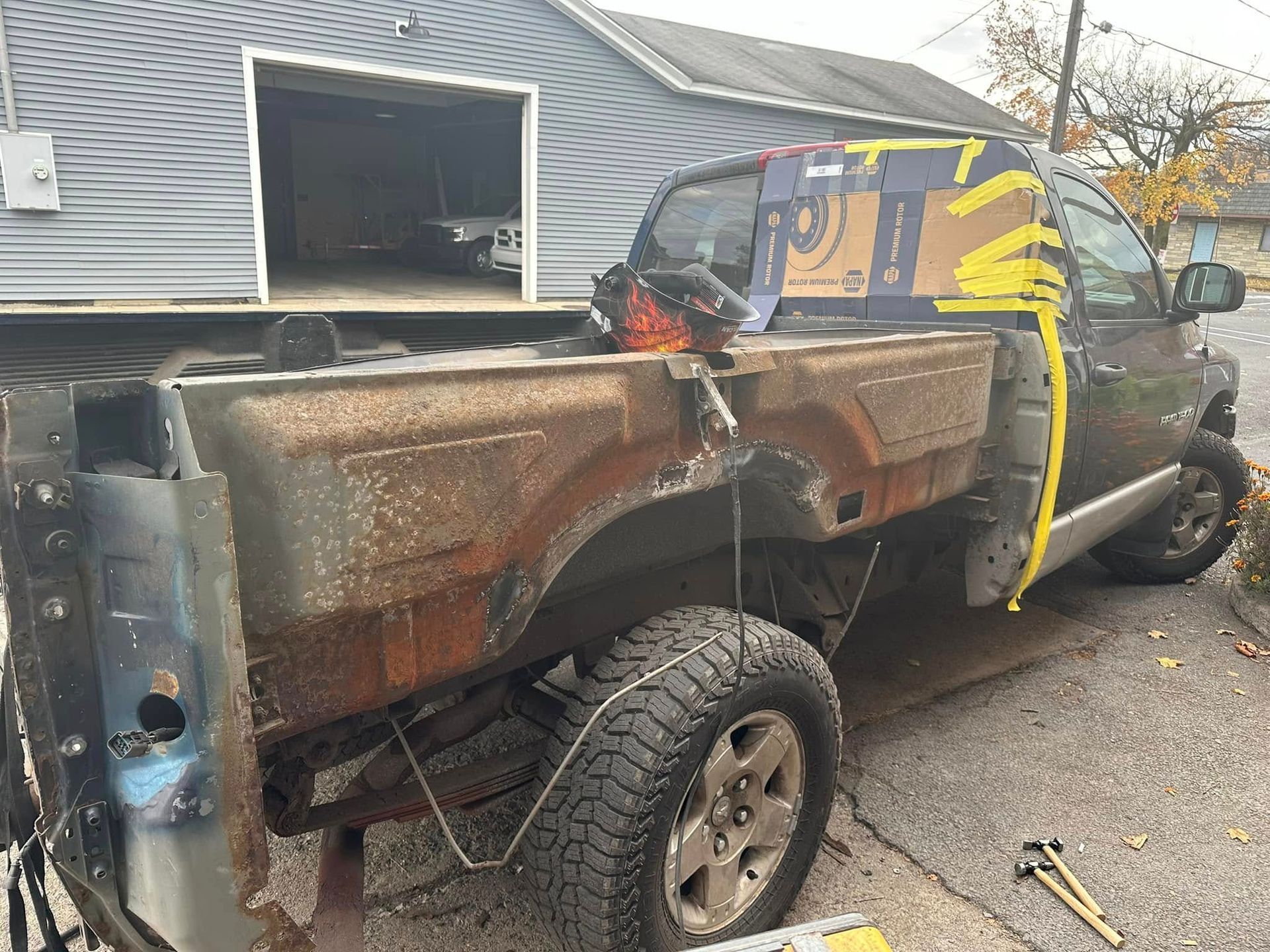 A truck is being worked on in front of a garage.