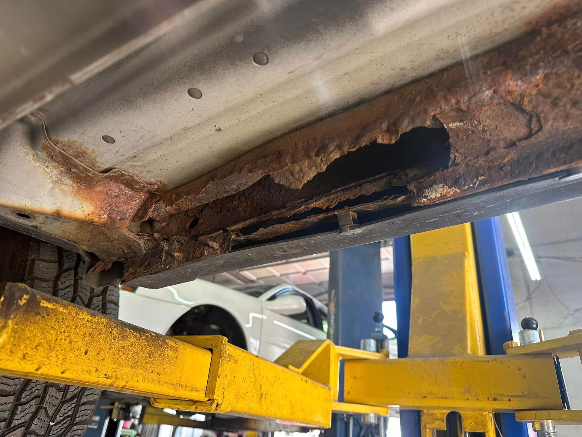 A car is sitting on top of a yellow lift in a garage.