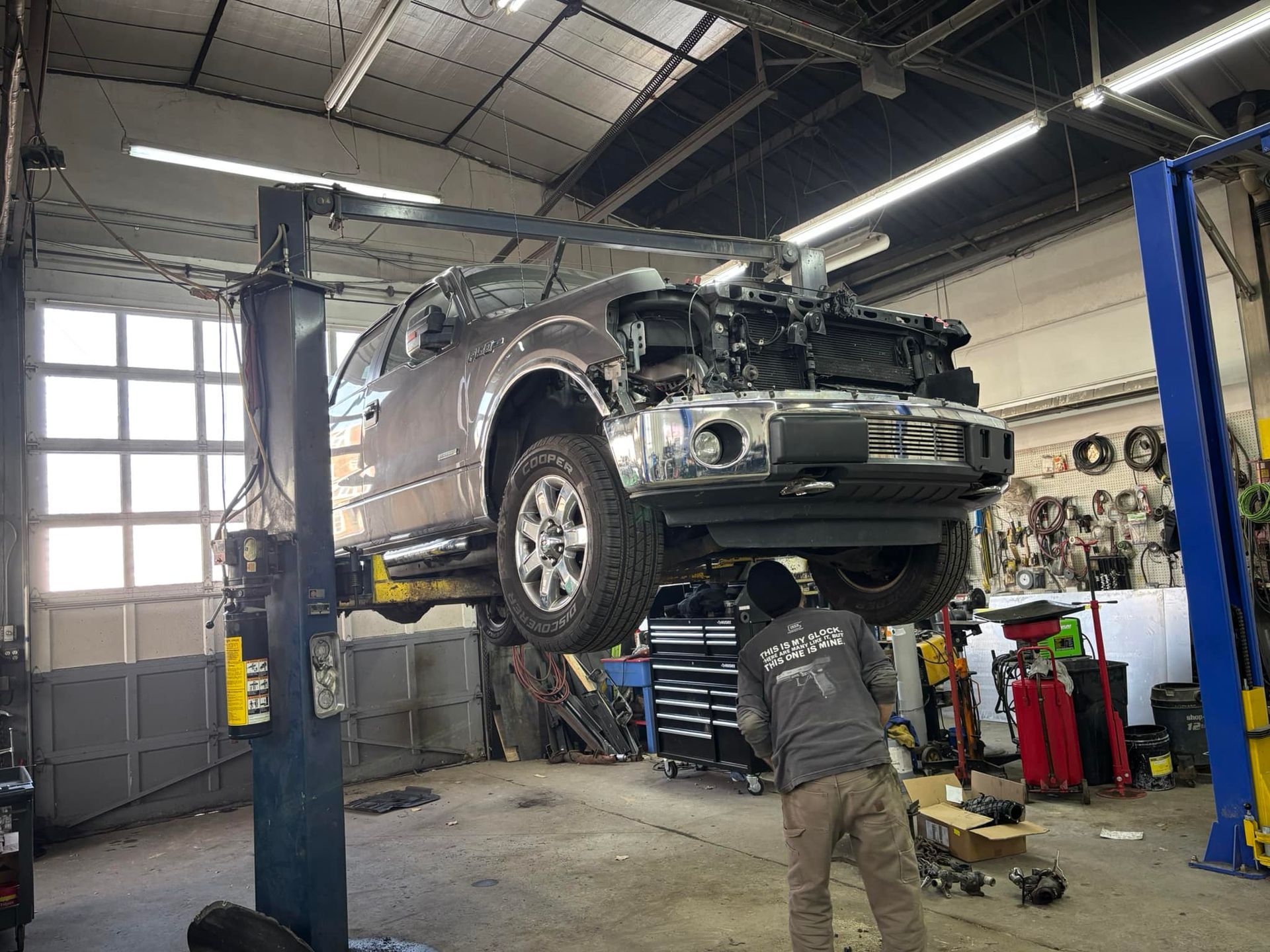 A man is working on a truck on a lift in a garage.