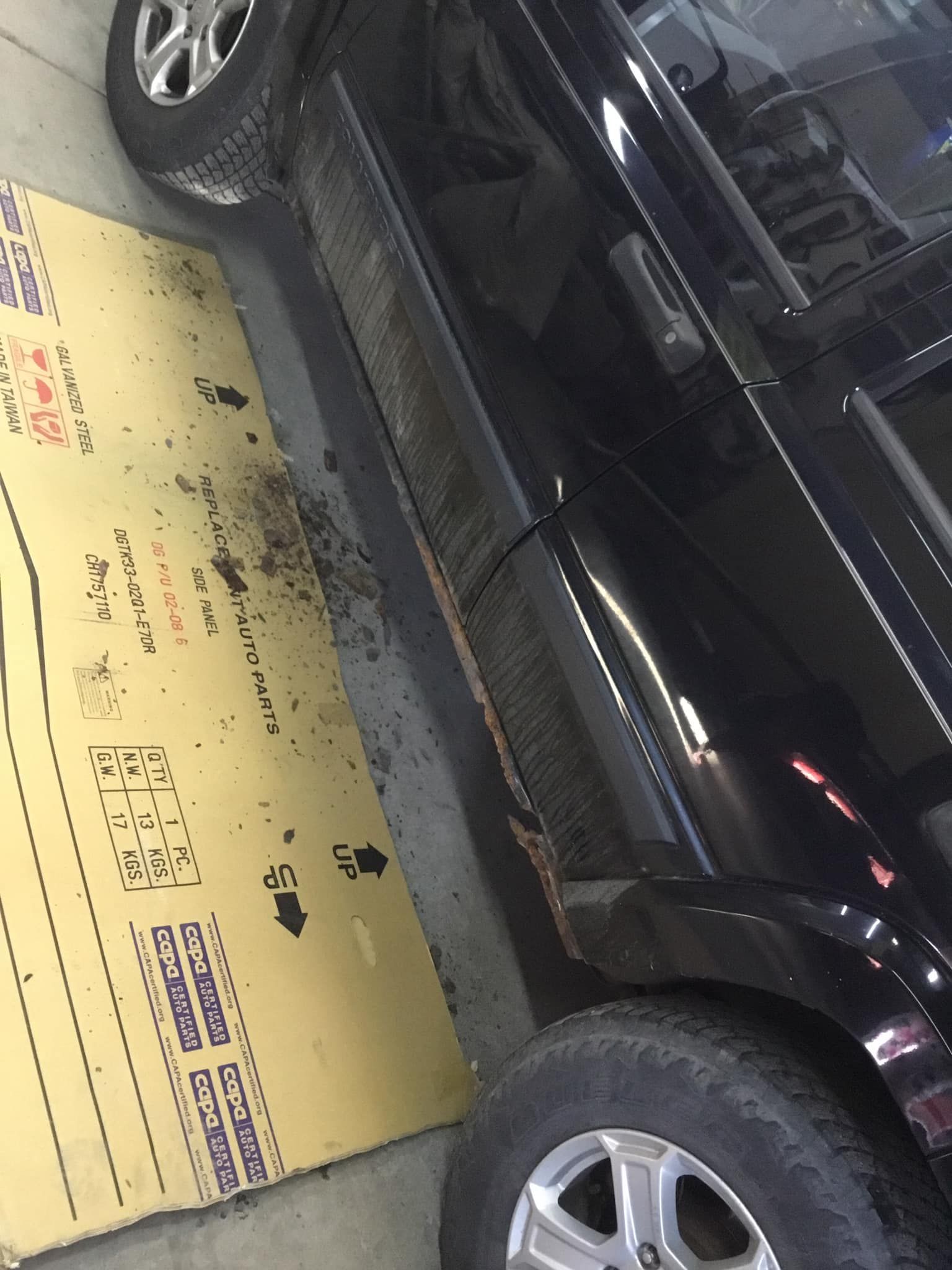 A black car is sitting on top of a cardboard box.