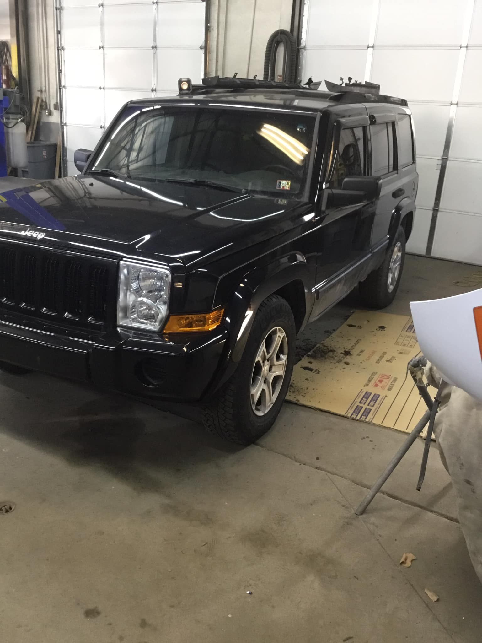 A black jeep is parked in a garage next to a white garage door.