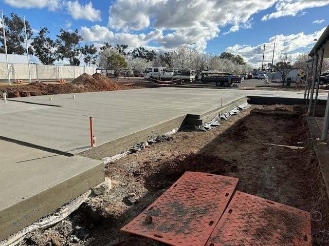 A Concrete Floor Is Being Built In A Backyard Next To A Green Fence — Lonnie Henderson Concreting In Dubbo, NSW
