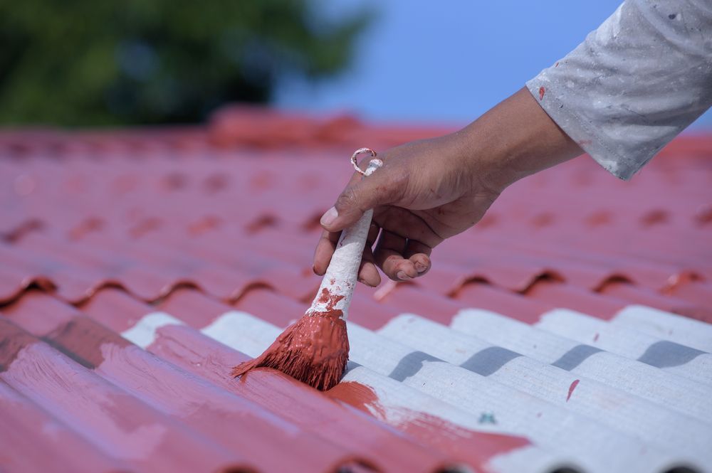 Hand Painting a Red Coating Onto a Corrugated Metal Roof — Israel Jones Painting in Rowes Bay, QLD
