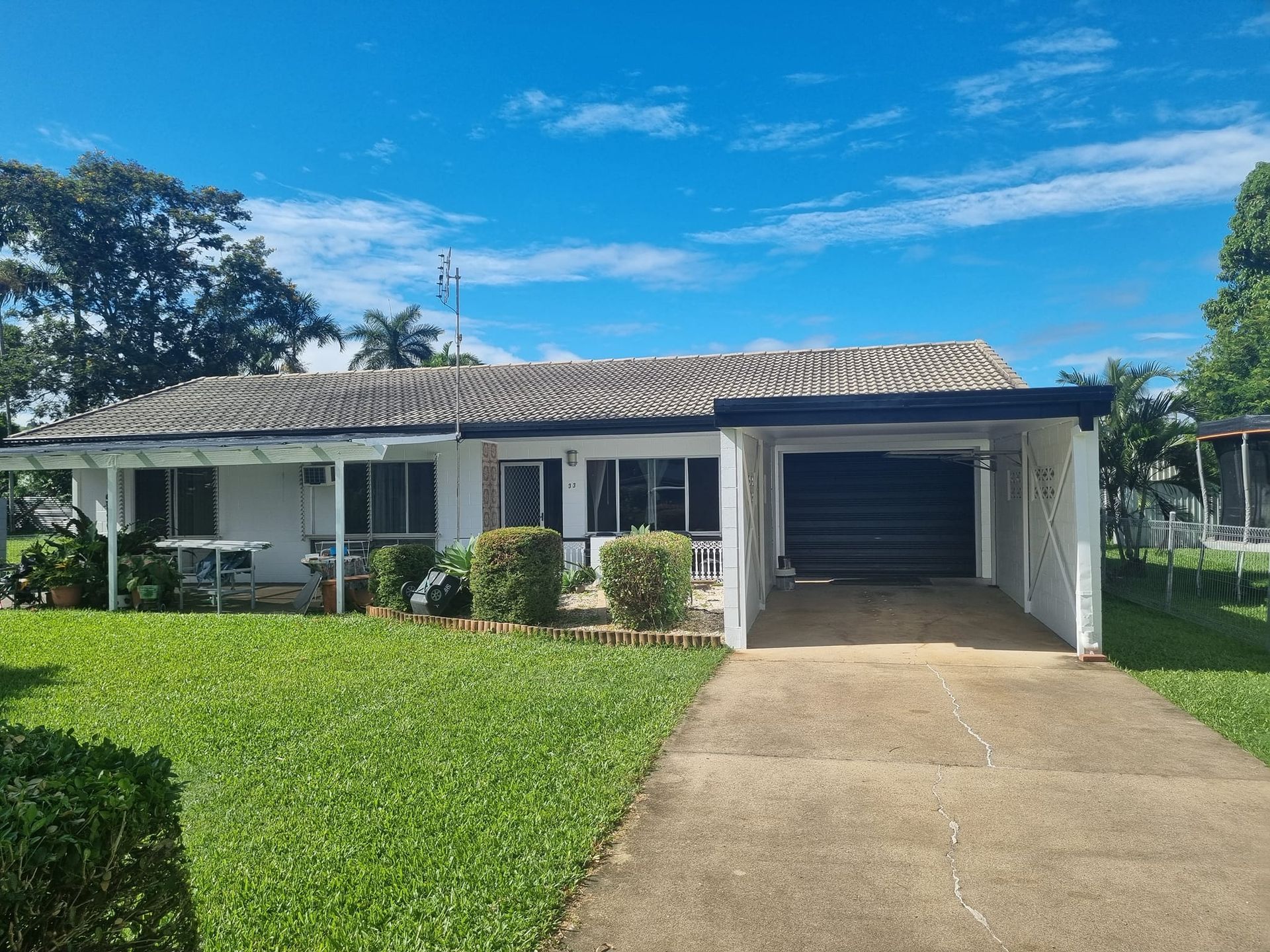 White Bungalow House With a Carport on a Sunny Day. Green Lawn — Israel Jones Painting in Vincent, QLD