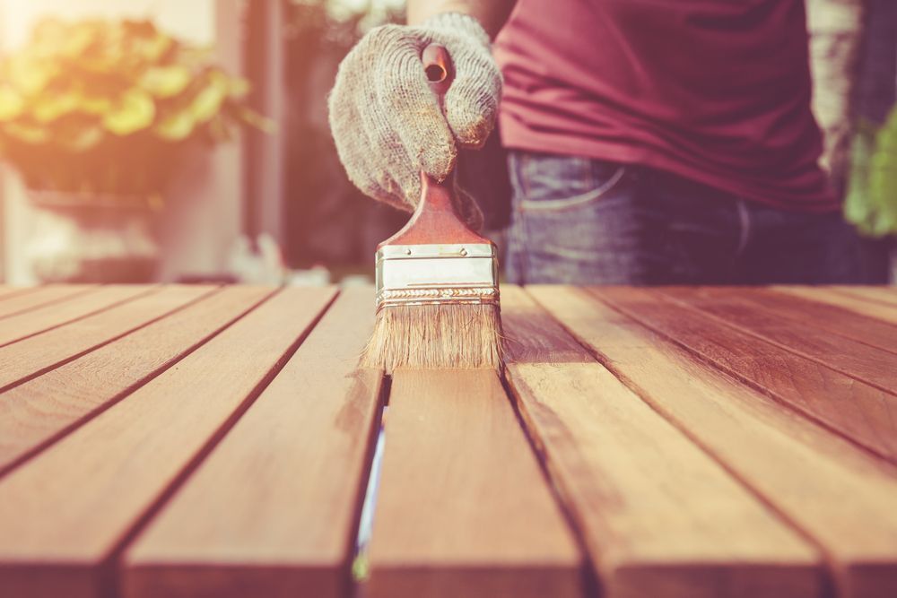 Person Applying Stain With a Brush to a Wooden Table — Israel Jones Painting in Rowes Bay, QLD