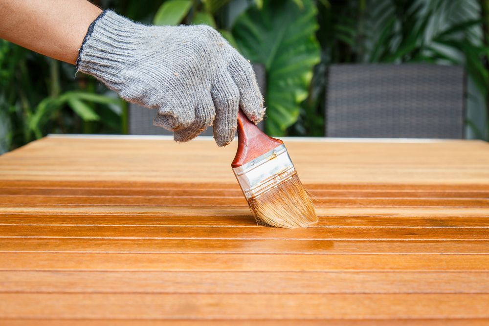 Gloved Hand Applying Stain to a Wooden Table — Israel Jones Painting in Rowes Bay, QLD