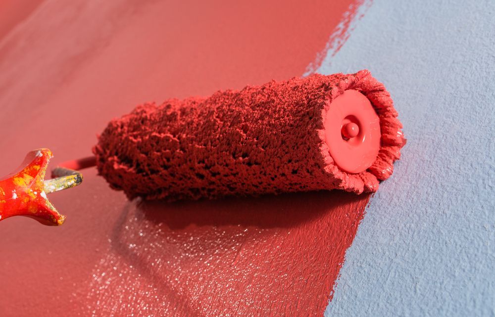 Paint Roller Applying Red Paint to a Light Blue Wall — Israel Jones Painting in Pallarenda, QLD