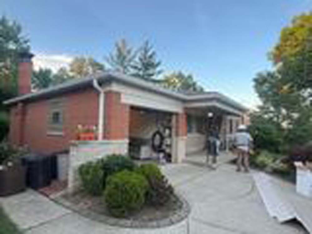 A group of people are standing in front of a brick house.