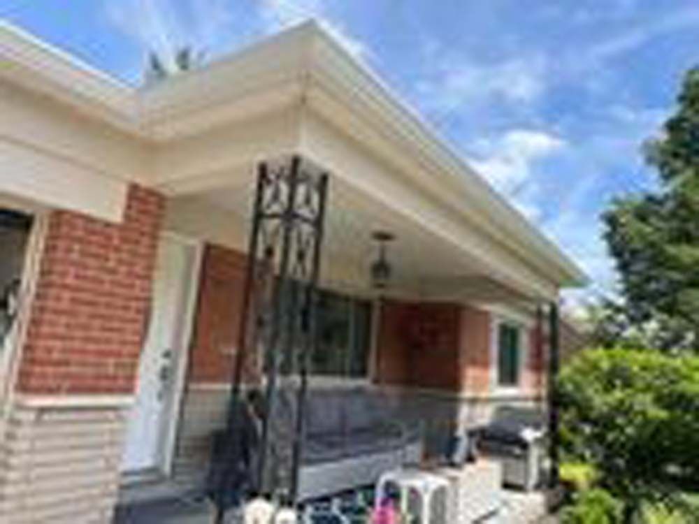 A brick house with a porch and a white gutter.