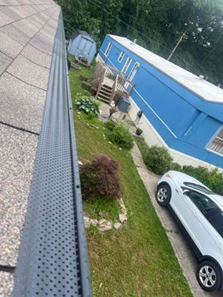 A white car is parked in front of a blue mobile home.