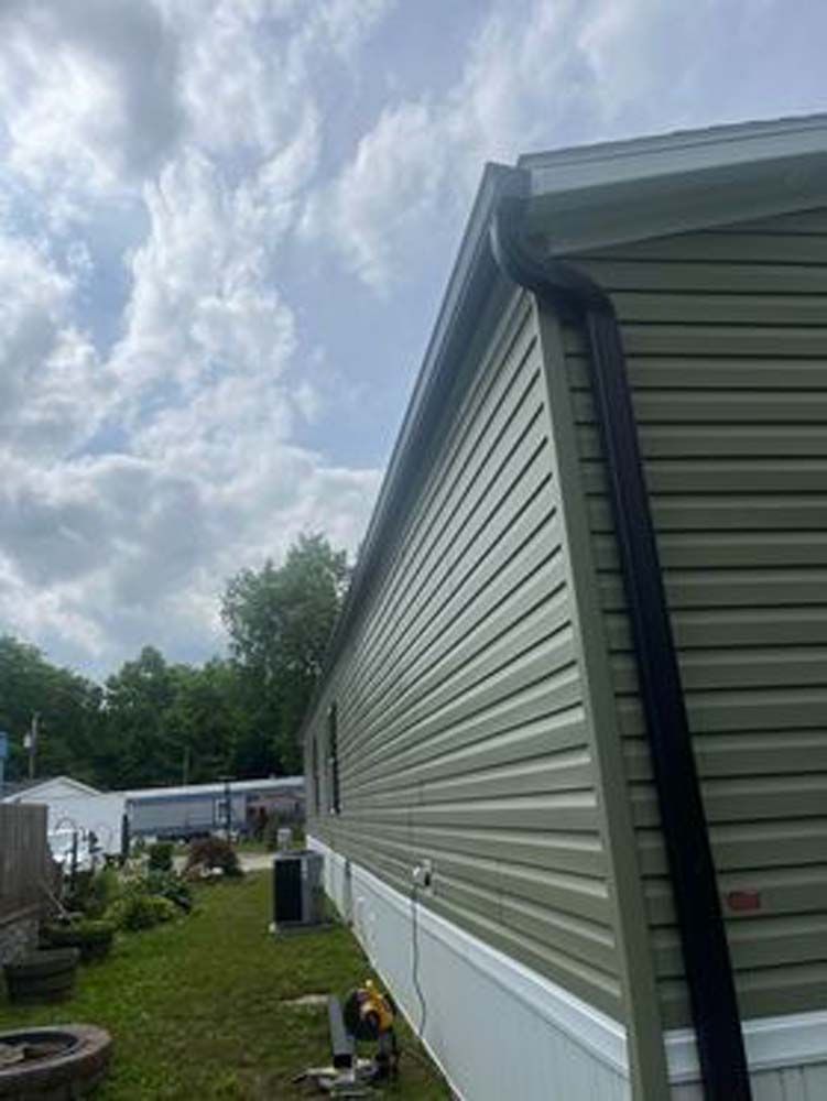 A mobile home with a black gutter on the side of it.
