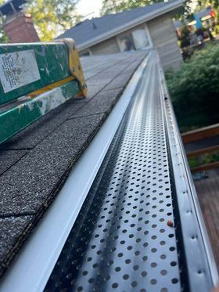 A ladder is sitting on top of a roof next to a gutter.