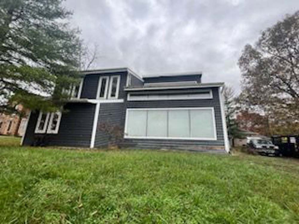 A large house with a lot of windows is sitting on top of a lush green field.