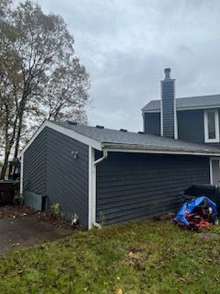 A gray house with a chimney on the side of it.