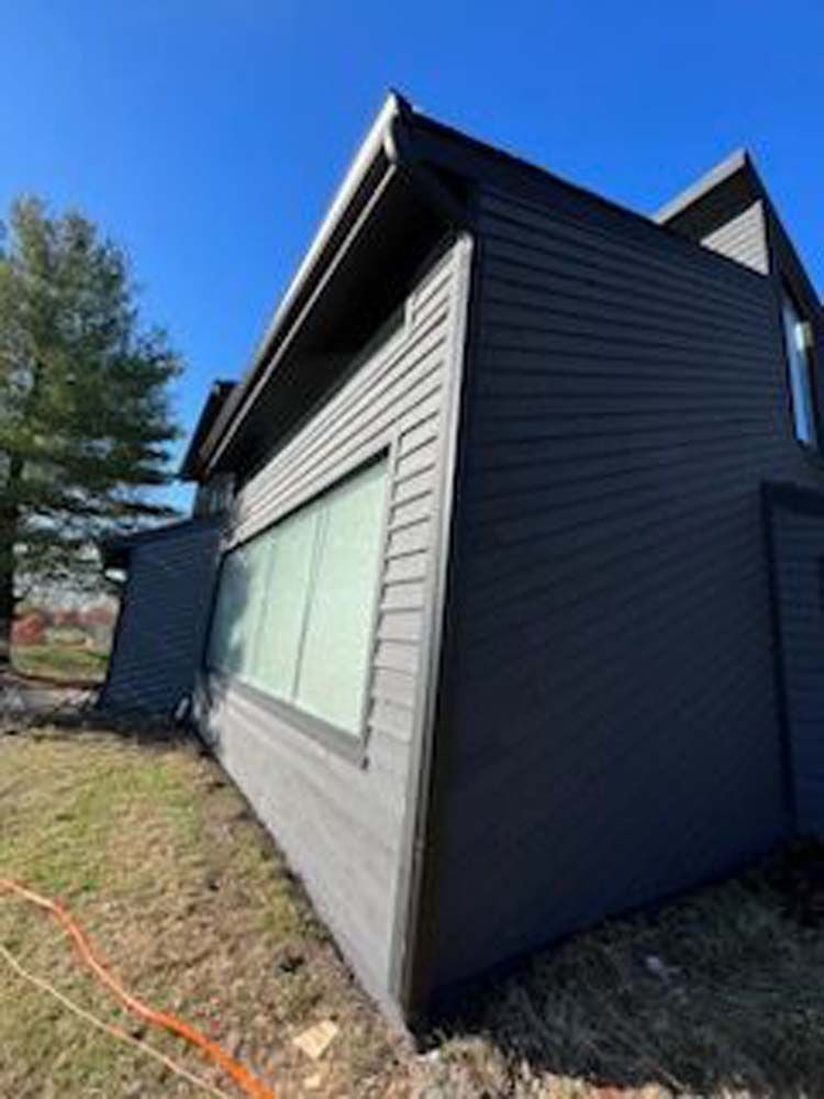 A large house with a lot of windows is sitting on top of a lush green field.