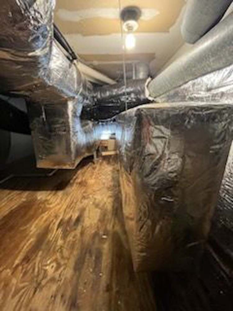 A room with a lot of ducts and a wooden floor.