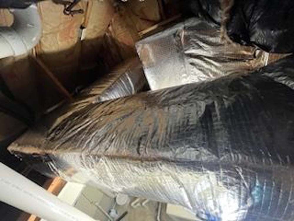 A bunch of ducts are wrapped in plastic in a room.