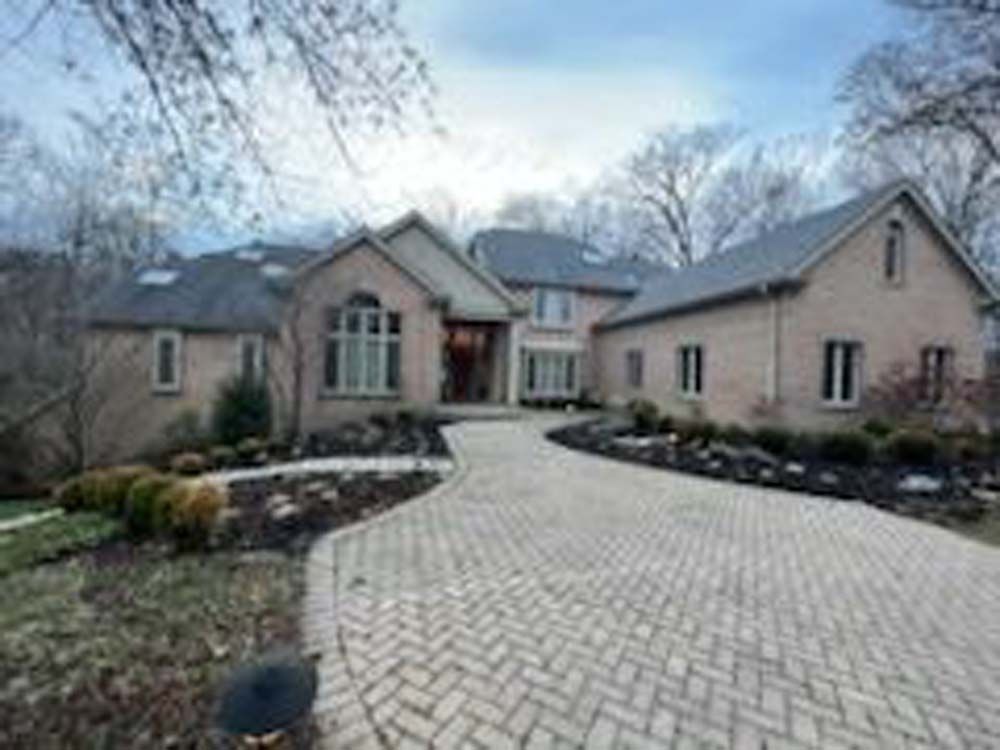 A large brick house with a brick driveway leading to it.