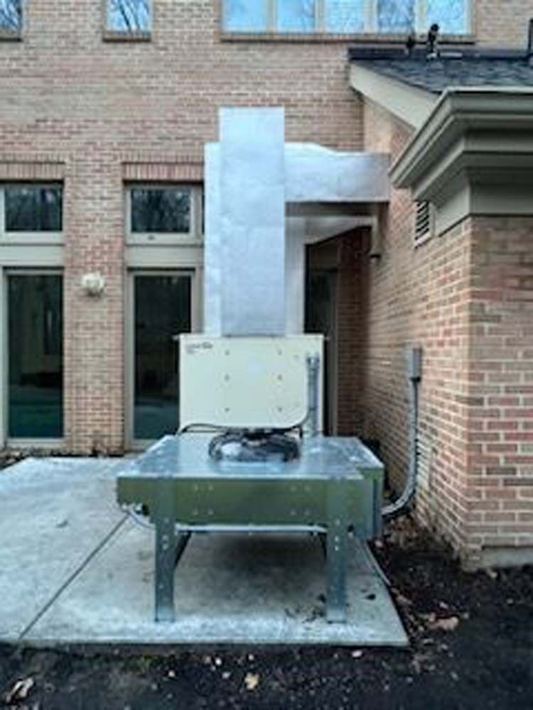 A large metal box is sitting on the side of a brick building.