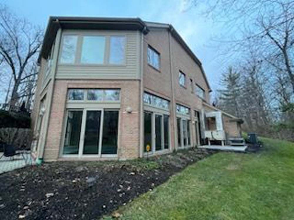 The back of a large brick house with a lot of windows.