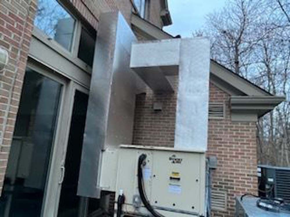 A large air conditioner is sitting outside of a brick building.