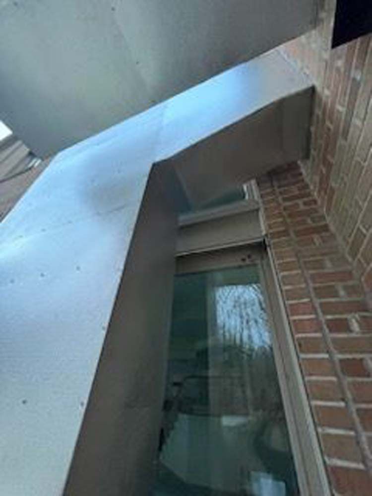 A brick building with a window and a metal roof.