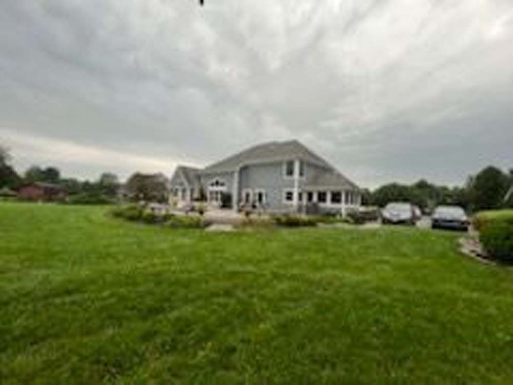 A large house is sitting on top of a lush green field.