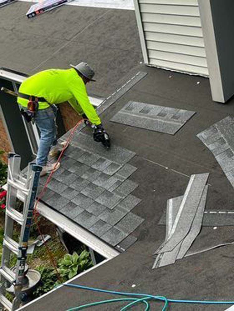 A man is standing on a ladder working on a roof.