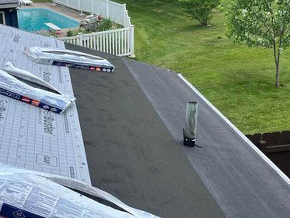 A roof with a chimney and a pool in the background.